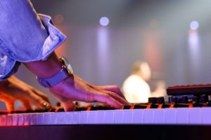 Musician playing keyboard on stage with band