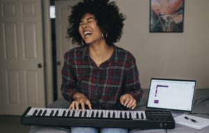 Happy woman playing keyboards and singing along.